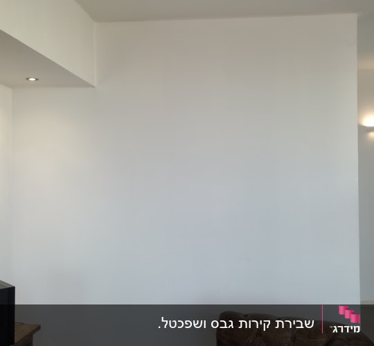 קיר ומחיצת גבס בסלון לצד סינר גבס בתקרה עם ספוט שקוע